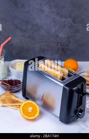 Slices of great toast coming out of the toaster. Healthy breakfast food and heating technology concept.  Focus on slice of great. Stock Photo