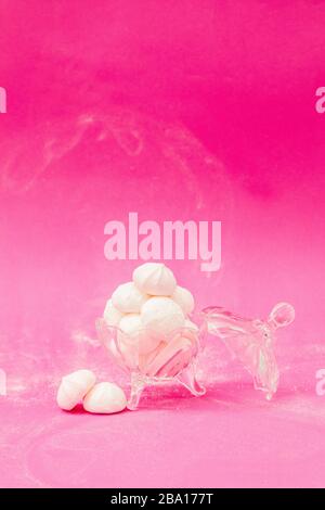 Meringues in a glass bowl on a pink background Stock Photo