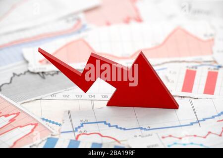 Financial crisis concept with falling red arrow on financial charts from newspapers Stock Photo