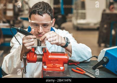 student of technical school on practical exam when working with vise and electric grinder Stock Photo