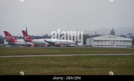 Glasgow, UK. 25th Mar, 2020. Pictured: Virgin Atlantic aircraft (Boeing 747-400 series - named Ruby Tuesday, registered G-VXLG) and an Airbus A330-200 - named Honkytonk Woman, registered G-VMIK) stand grounded on the tarmac by the Logan Air hanger. Credit: Colin Fisher/Alamy Live News Stock Photo