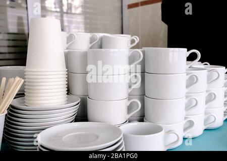 Exposed on stacks of white clean ceramic cups and saucers. The dishes in the restaurant are prepared for tea drinking and coffee drinking. Stock Photo