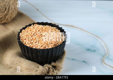 Yellow dry beans in a black plastic bowl on a piece of blue marble Stock Photo