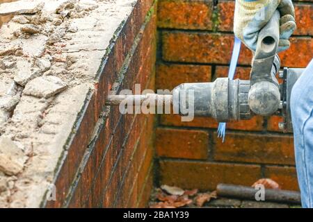 CARDIFF, WALES - JANUARY 2020: Worker using a power hammer to break up bricks in an old wall. Stock Photo