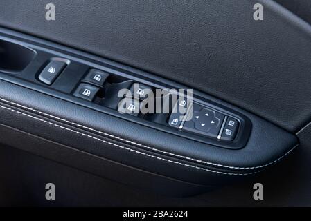 Image in closeup of a door control panel in a modern car. Arm rest with window control panel, door lock button, and mirror control Stock Photo