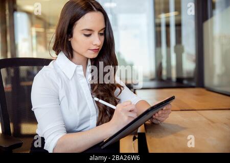 Creative designer working in office space on tablet technology device, possibly journalist, writer or digital artist Stock Photo
