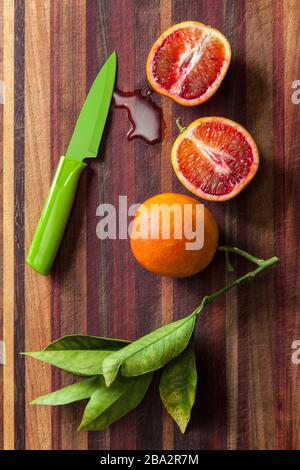 sliced blood oranges and paring knife on a wooden cutting board Stock Photo