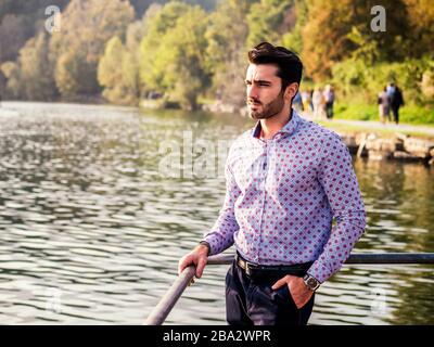 Young man wearing beside picturesque river or lake Stock Photo
