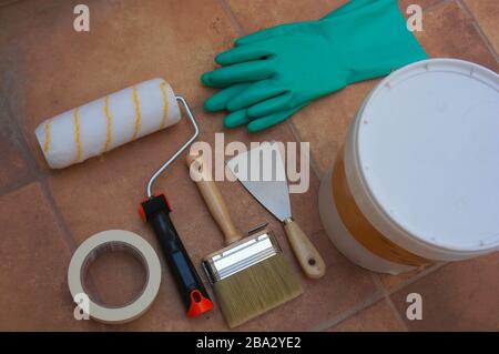 Flat lay of set of elements related to painting and decoration of the house, such as a brush, a pot of paint, gloves, a curler, a pallet and body tape Stock Photo