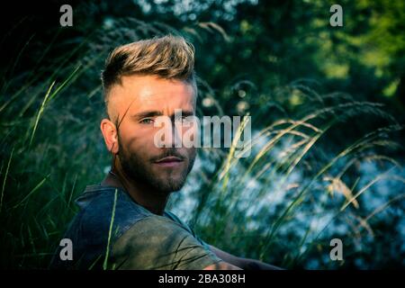 Blondish, blue eyed young man by river Stock Photo