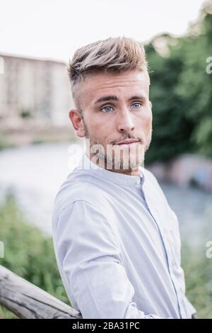 Blondish, blue eyed young man by river smiling Stock Photo