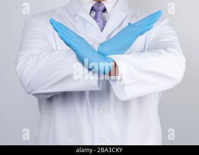 doctor man in a white coat and blue latex gloves crossed his arms in front of his chest, gesture of rejection, denial Stock Photo