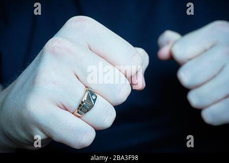 The man put menacingly fists with a ring on. Blue toned. Close up. Stock Photo