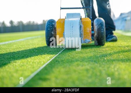 Lining a football pitch using white paint on grass Stock Photo