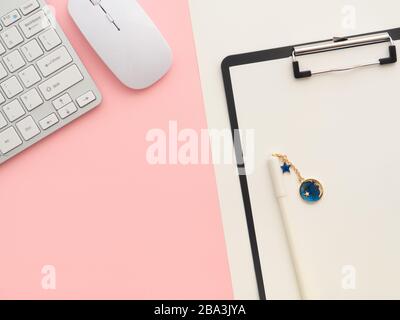 Real photo, black clipboard with blank a4 paper mockup template with white pen on it, isolated on beige and keyboard and mouse on pink background with Stock Photo