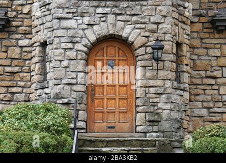 Round top wood panel door of house built of rough hewn stone Stock Photo