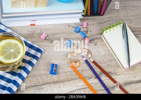 A stack of books, a clock, wooden cubes in the shape of a pyramid, next to there is tea with lemon in a transparent glass glass and multi-colored Stock Photo