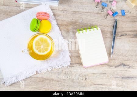 An open notebook with a silver pen, a cup of mint tea with lemon and multi-colored muffins stand next to it Stock Photo