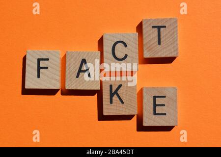 Fact and Fake, words in wooden alphabet letters on orange coloured background Stock Photo