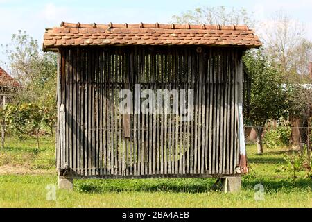 Front view of dilapidated old wooden corn shed used for drying and storing corn cobs made from narrow vertical wooden boards Stock Photo