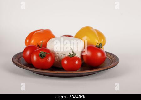 Cheese, tomato and peppers in a brown plate Stock Photo