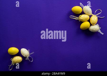 Yellow and white plastic easter decorative eggs on a dark purple background Stock Photo