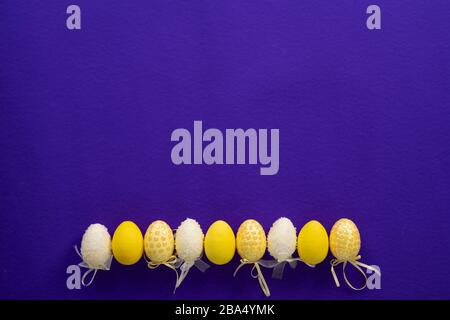 Easter white and yellow plastic decorative eggs on a dark purple background Stock Photo