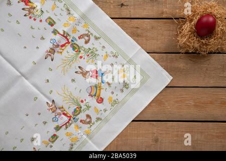 Easter background with an easter tablecloth and a nest with an egg on a wooden surface Stock Photo
