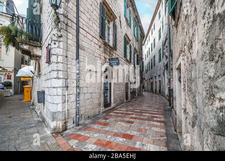 Small shops and cafes line a picturesque medieval street in the old town district of the coastal city of Kotor, Montenegro, on the Adriatic Coast. Stock Photo