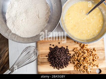 Making banana bread in mixing bowls with walnuts and chocolate chips, overhead view Stock Photo