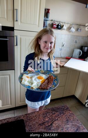 Young girl with pride showing her just cooked breakfast of bacon and eggs. Zawady Gmina Rzeczyca Poland Stock Photo