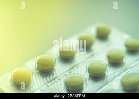 Blister with yellow vitamins on the table, one vitamin is already eaten, close-up, side view. Stock Photo