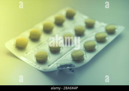 Blister with yellow vitamins or pills on the table, one vitamin is already eaten, close-up, side view. Stock Photo