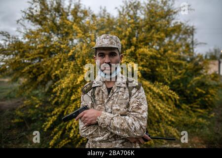 Tripoli, Libya. 25th Mar, 2020. A UN-backed Government of National Accord (GNA) fighter with a mask poses at Ain-Zara frontline in Tripoli, Libya, March 25, 2020. The Minister of Health of Libya's UN-backed government, Ehmid Bin Omar, on Tuesday announced the first novel coronavirus infection in the country. Credit: Amru Salahuddien/Xinhua/Alamy Live News Stock Photo
