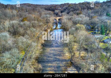 Aerial View of Woods in Fall Colors with a Road, Stream and Railroad Bridge Stock Photo