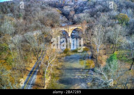 Aerial View of Woods in Fall Colors with a Road, Stream and Railroad Bridge Stock Photo