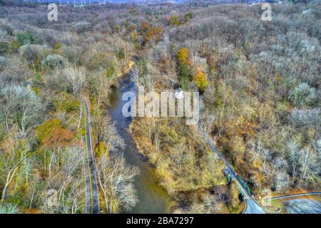 Aerial View of Woods in Fall Colors with a Road, Stream and House Stock Photo