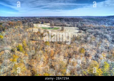 Aerial View of Woods in Fall Colors with a Farmhouse Stock Photo