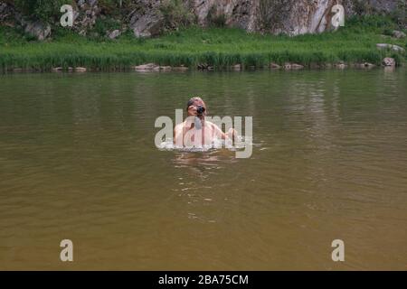 photographer holding waterproof camera and swimming in river, trying to catch some interesting shots. Professional photographer job concept. Work in d Stock Photo