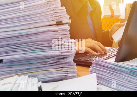 documents on desk stack up high waiting to be managed. Stock Photo