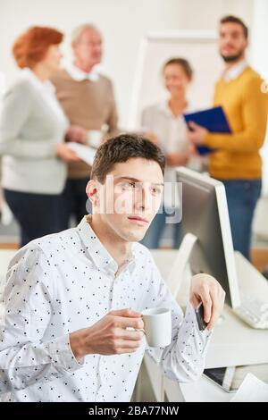 Thoughtful man sitting in front of his team having coffee in the office Stock Photo