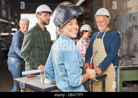 Smiling young woman as a welder in the team of a locksmith workshop Stock Photo