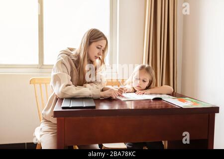 Mother helping her daughter making school homework at home. Learning at home, online learning, self quarantine, Home schooling and concept of COVID-19 Stock Photo