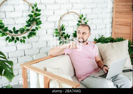 Man working on laptop and holding a pen thought Stock Photo