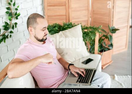 Man sitting on sofa using notebook looking on monitor Stock Photo