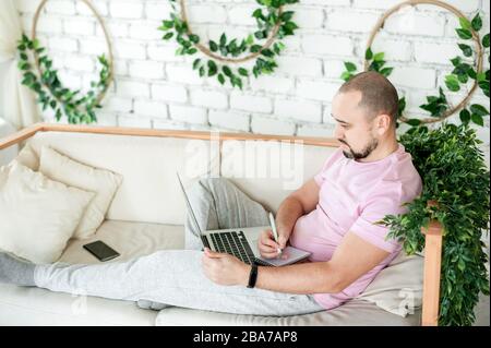 Man using laptop and taking notes at home Stock Photo