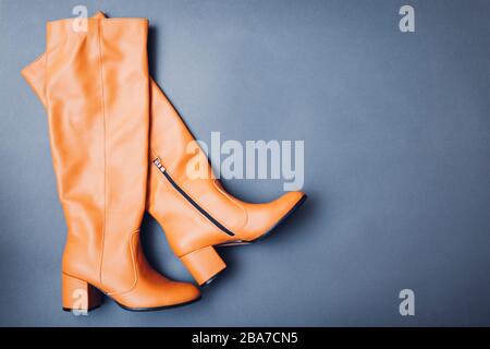 Shoes, stylish leather boots for women. Female winter, autumn or spring fashion. Orange caramel footwear. Space Stock Photo