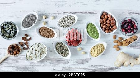 Small white bowls with various superfoods on white wooden background top view. Healthy eating concept. Stock Photo