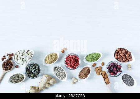 Small white bowls with various superfoods on white wooden background top view. Healthy eating concept. Copy space. Stock Photo