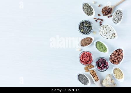 Small white bowls with various superfoods on white wooden background top view. Healthy eating concept. Copy space. Stock Photo